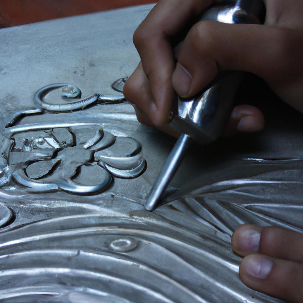 Person carving intricate design on metal plate