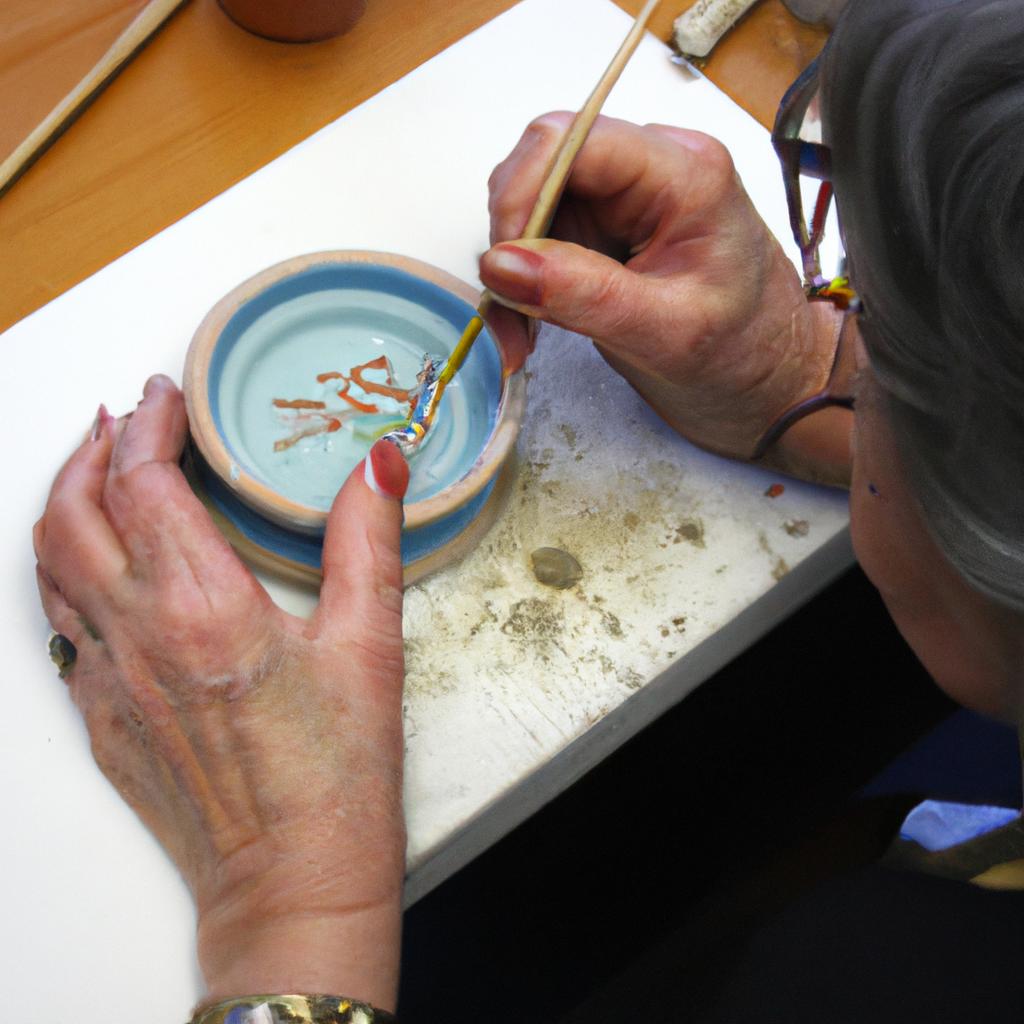 Person glazing ceramic artwork demonstration